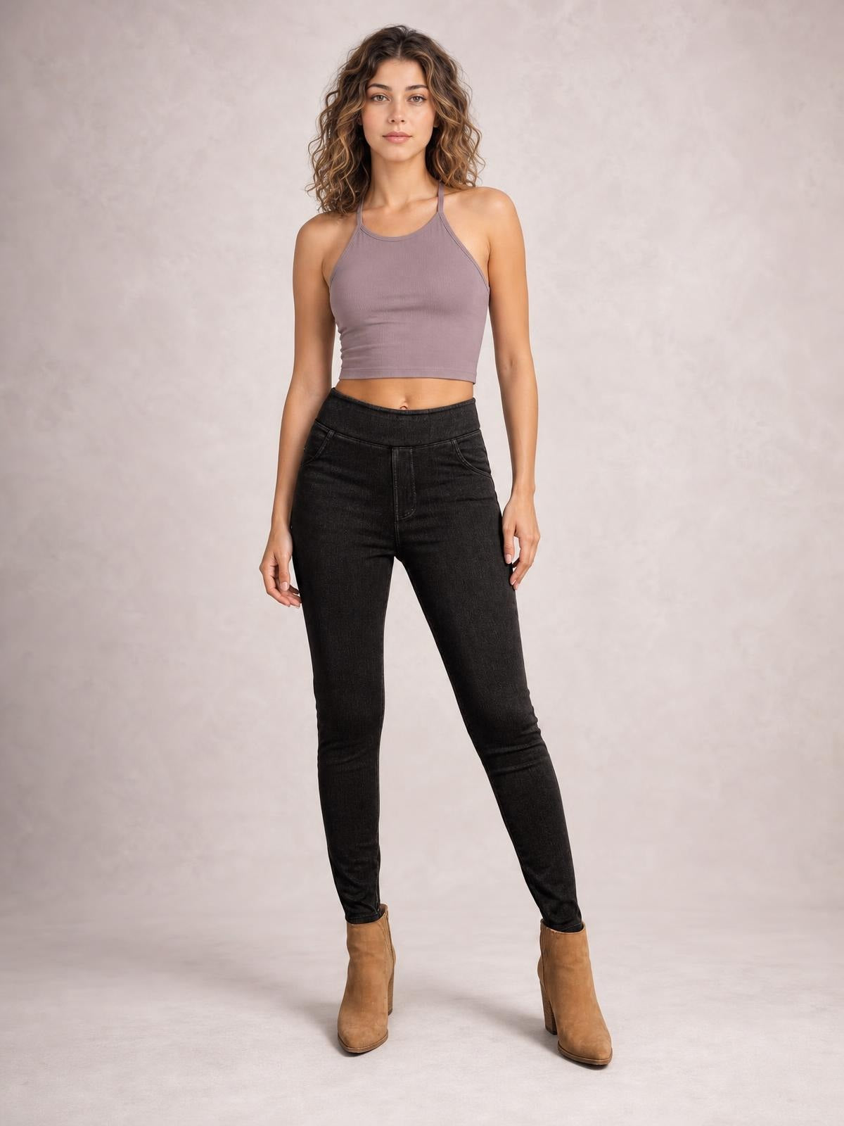 Model wearing black skinny jeans with visible front pockets, a high-rise waistband, fitted stretch silhouette, and tapered legs, posed standing with one leg angled outward.