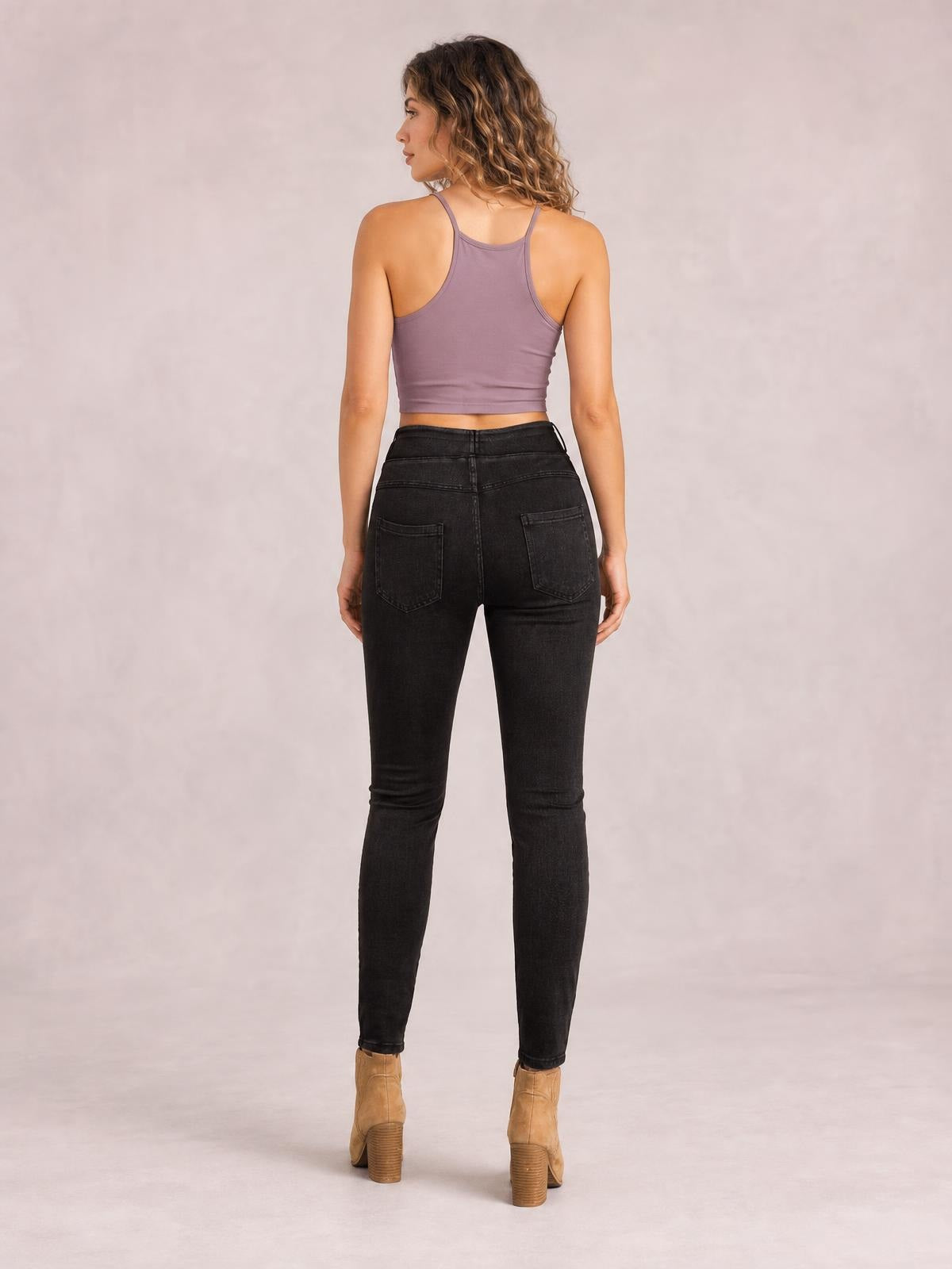 Model viewed from behind wearing black skinny jeans with back pockets, a fitted high-rise silhouette, and tapered legs.