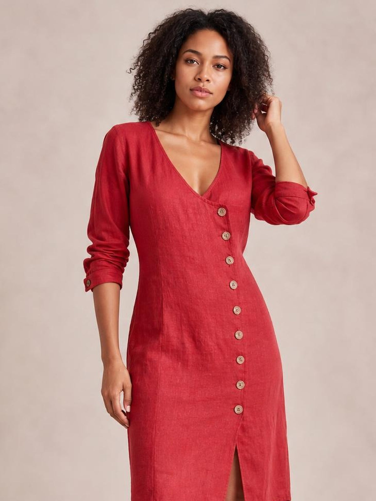 Model poses in a red button-down midi dress with a V-neckline, long cuffed sleeves, fitted silhouette, and front slit.