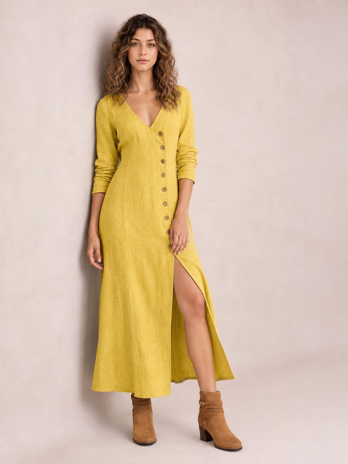 Model poses in a mustard yellow midi dress with a V-neck, long sleeves, button-down front, straight silhouette, and thigh-high side slit.