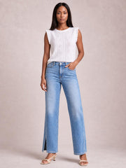 Model wears light blue slit buttoned jeans with pockets, a high waist, straight-leg silhouette, and ankle-length hems, posing with one hand in a pocket.