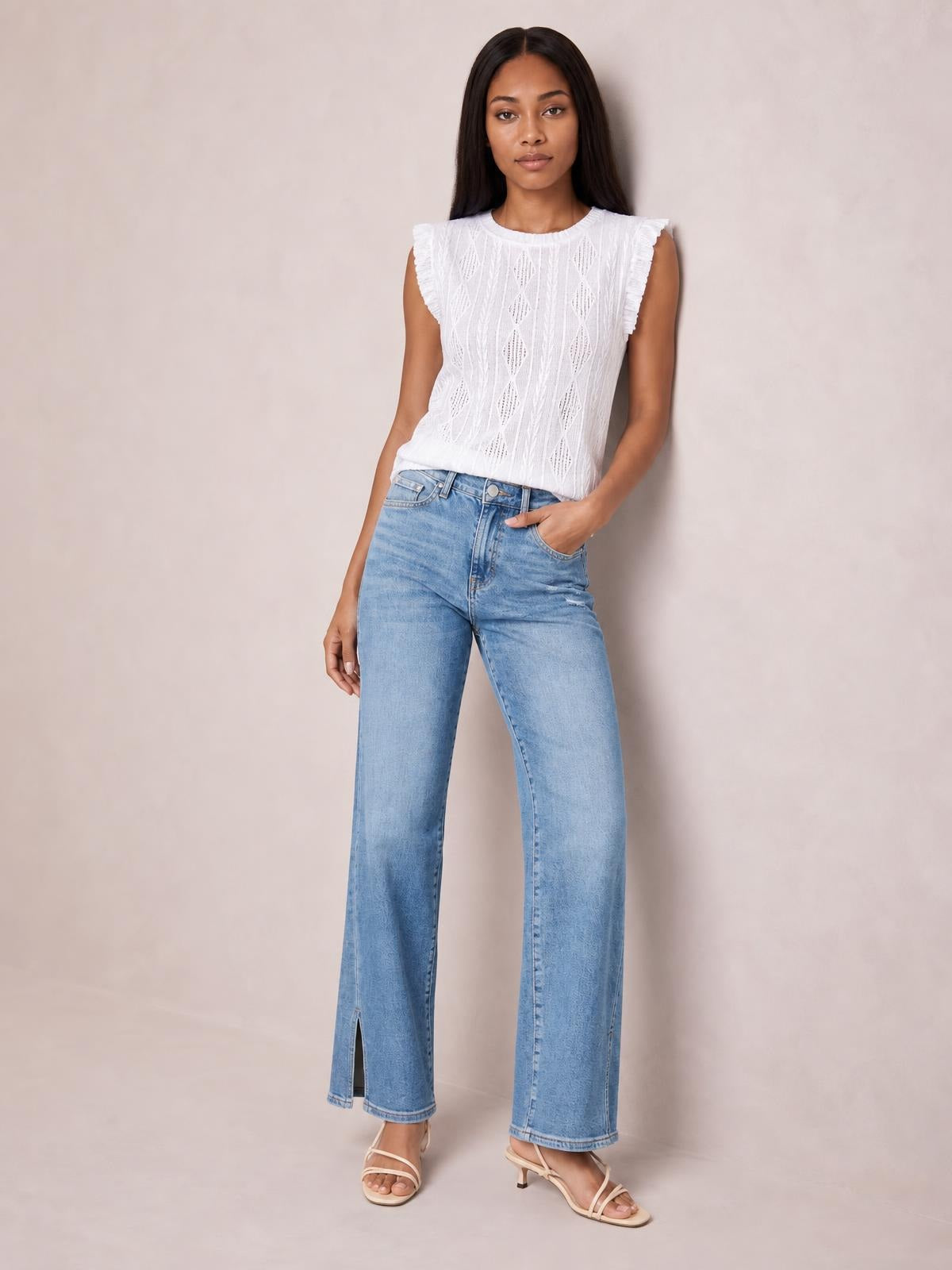 Model poses in light blue straight-leg jeans with front pockets, button closure, moderate stretch, and subtle ankle slits at the hems.