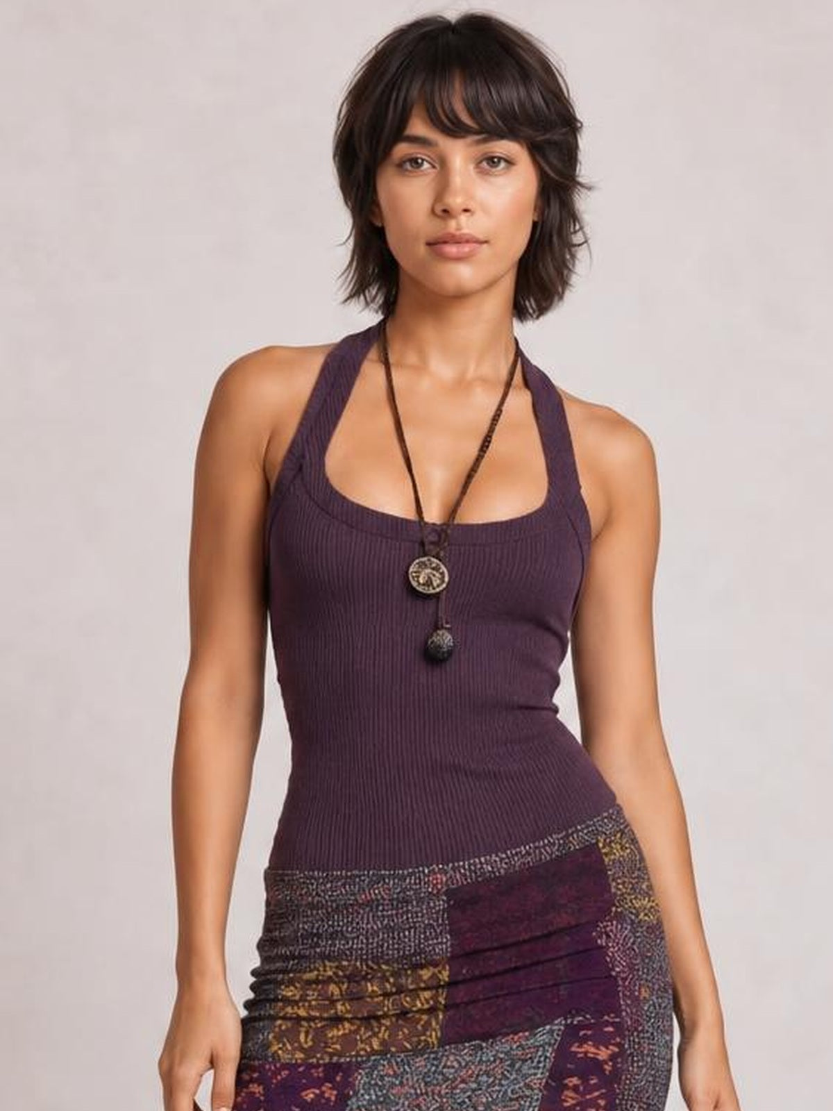 Model wears a fitted sleeveless midi dress with a deep purple ribbed bodice, scoop neckline, and multicolored printed skirt visible below the waist.