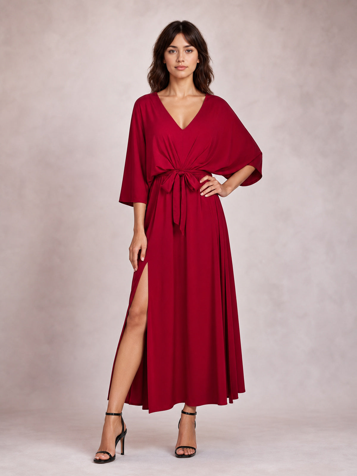 Model poses in a flowing burgundy V-neck dress with tied waist, relaxed three-quarter sleeves, flattering draped silhouette, and daring thigh-high side slit.