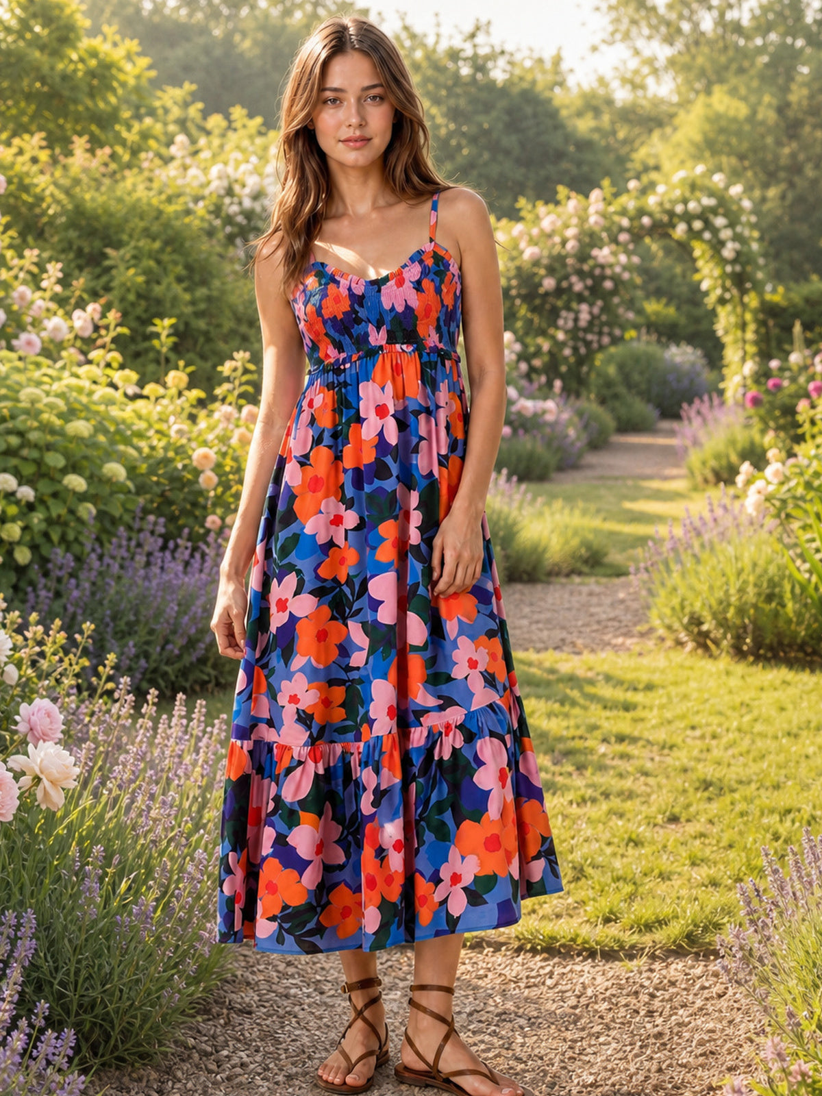 Model stands in a multicolor floral cami dress with slim straps, a smocked ruched bodice, flowing midi silhouette, and gathered ruffled hem.