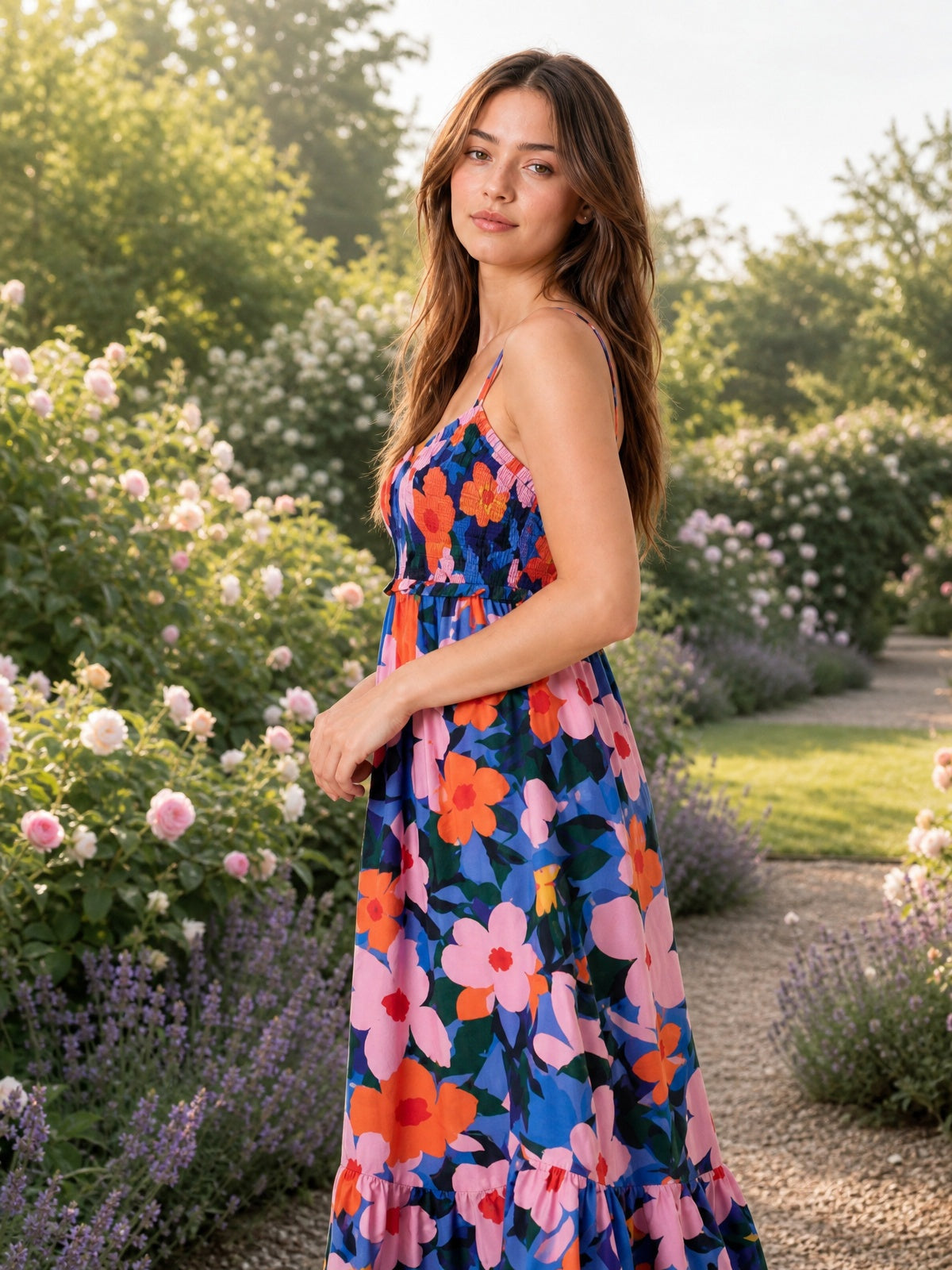 A model turns in a vibrant multicolor floral cami dress with slim straps, a ruched bodice, flowing silhouette, and gathered ruffled hem.