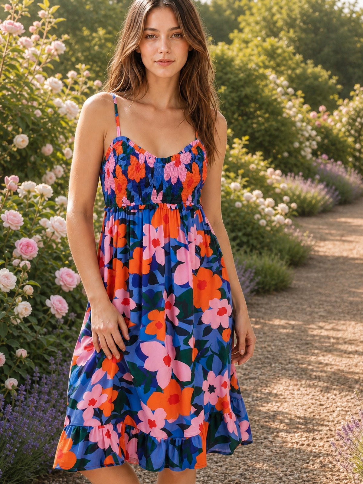 A model stands in a multicolor floral printed cami dress with slim straps, a ruched smocked bodice, flowing gathered skirt, and playful ruffled hem.