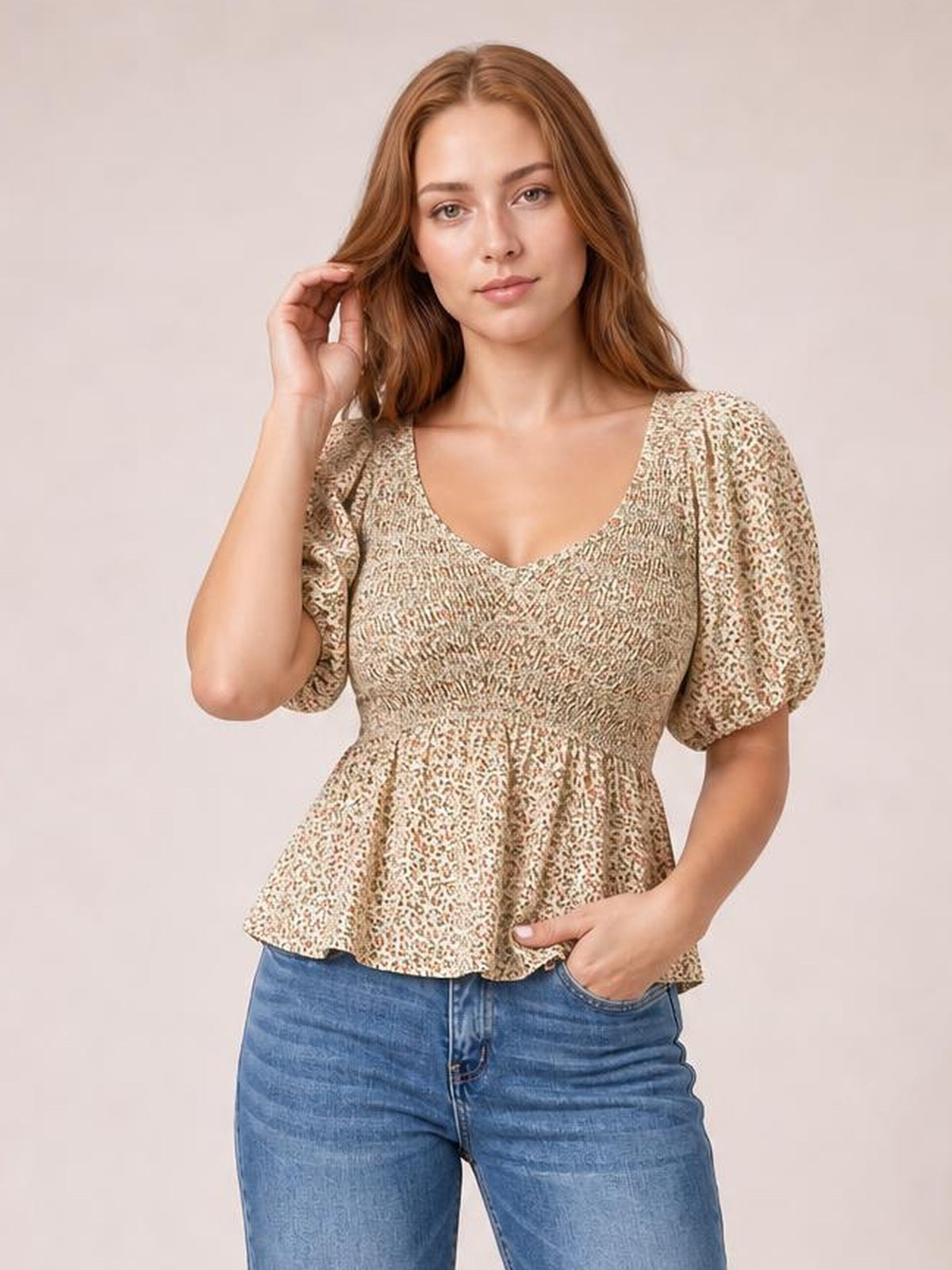 Model poses in a floral smocked peplum blouse with a V-neck, short balloon puff sleeves, and a flared waist silhouette.