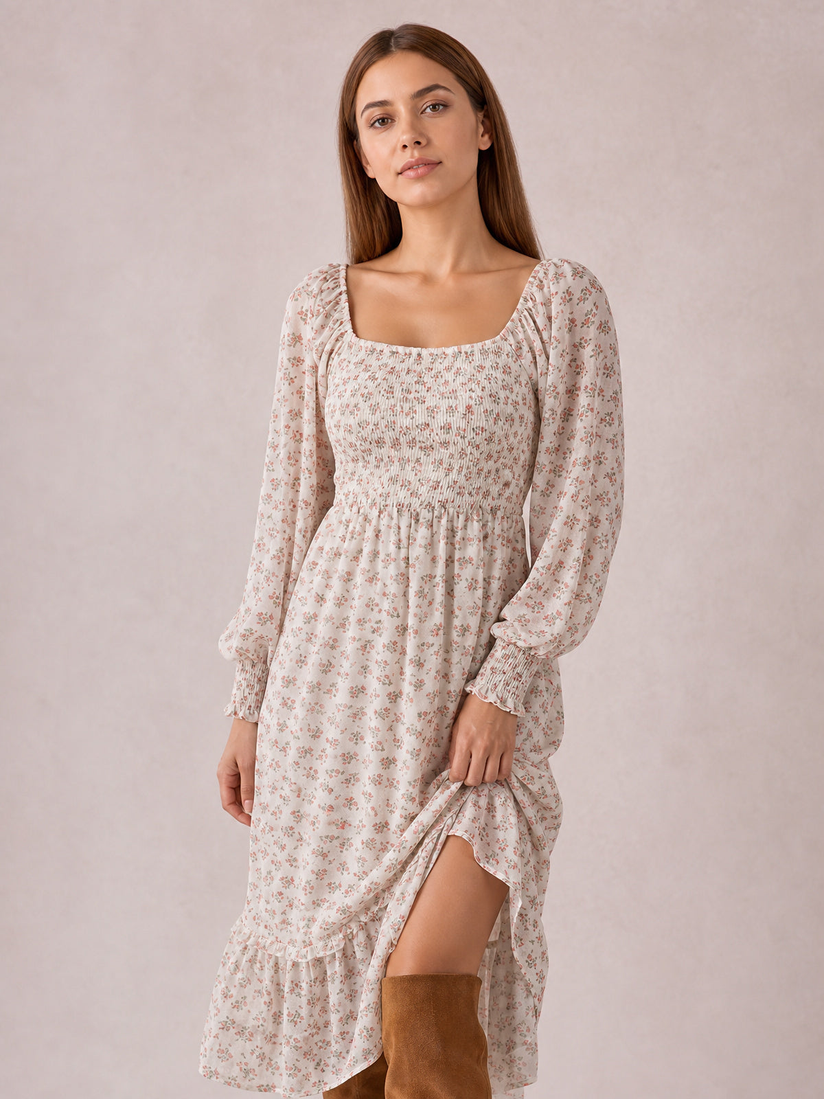 A model poses in a cream floral midi dress with a square neckline, long sleeves, smocked bodice, gathered skirt, and flounced hem, lifting the side to show brown boots.