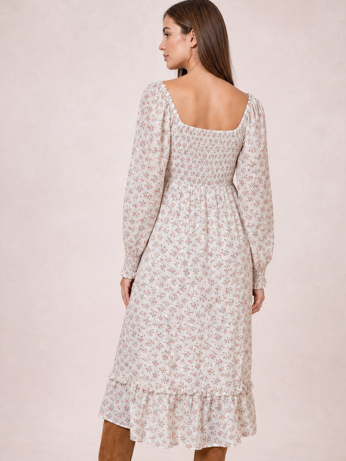 Model shown from the back in a floral midi dress with a square neckline, long sleeves, smocked bodice, flowing silhouette, and flounced hem.