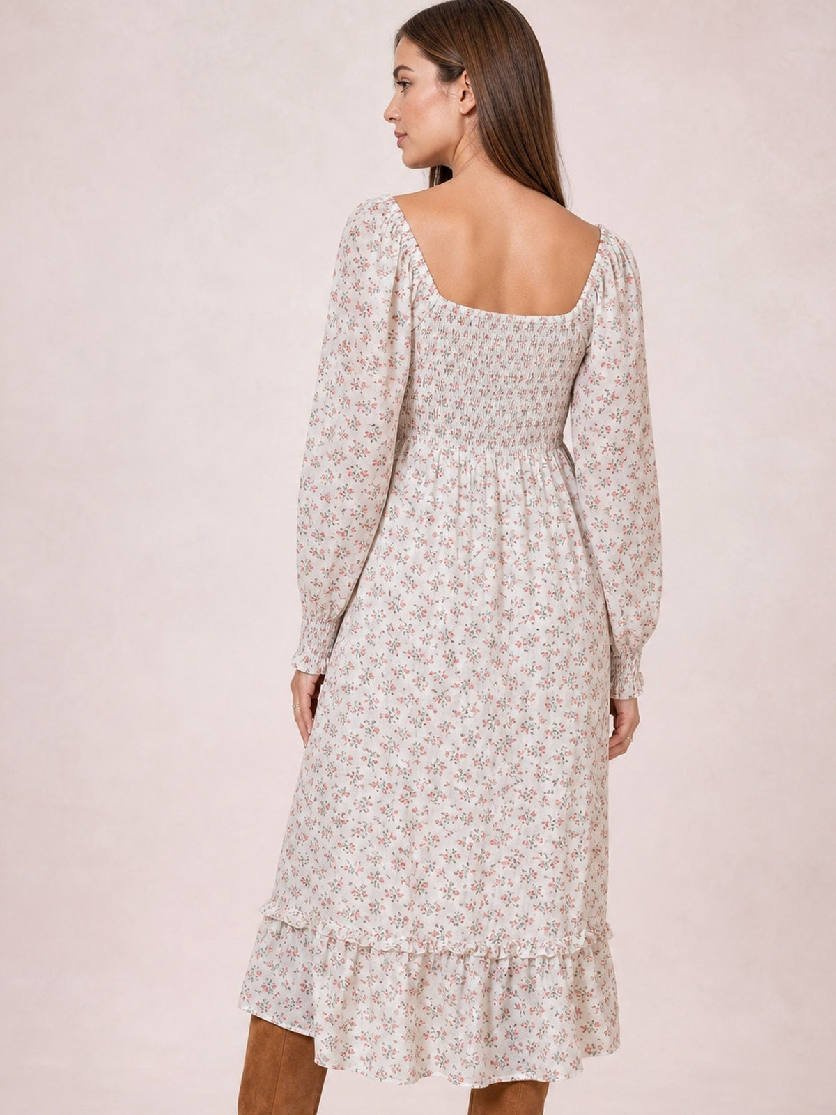 Model shown from the back in a floral midi dress with a square neckline, long sleeves, smocked bodice, flowing silhouette, and flounced hem.