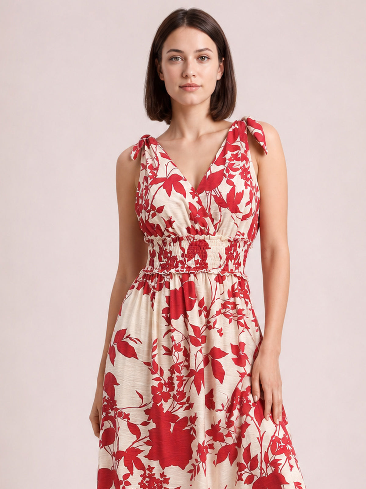 Model in a deep red and cream printed surplice midi dress with a V-neckline, tied shoulders, smocked waist, and flowing floral skirt.