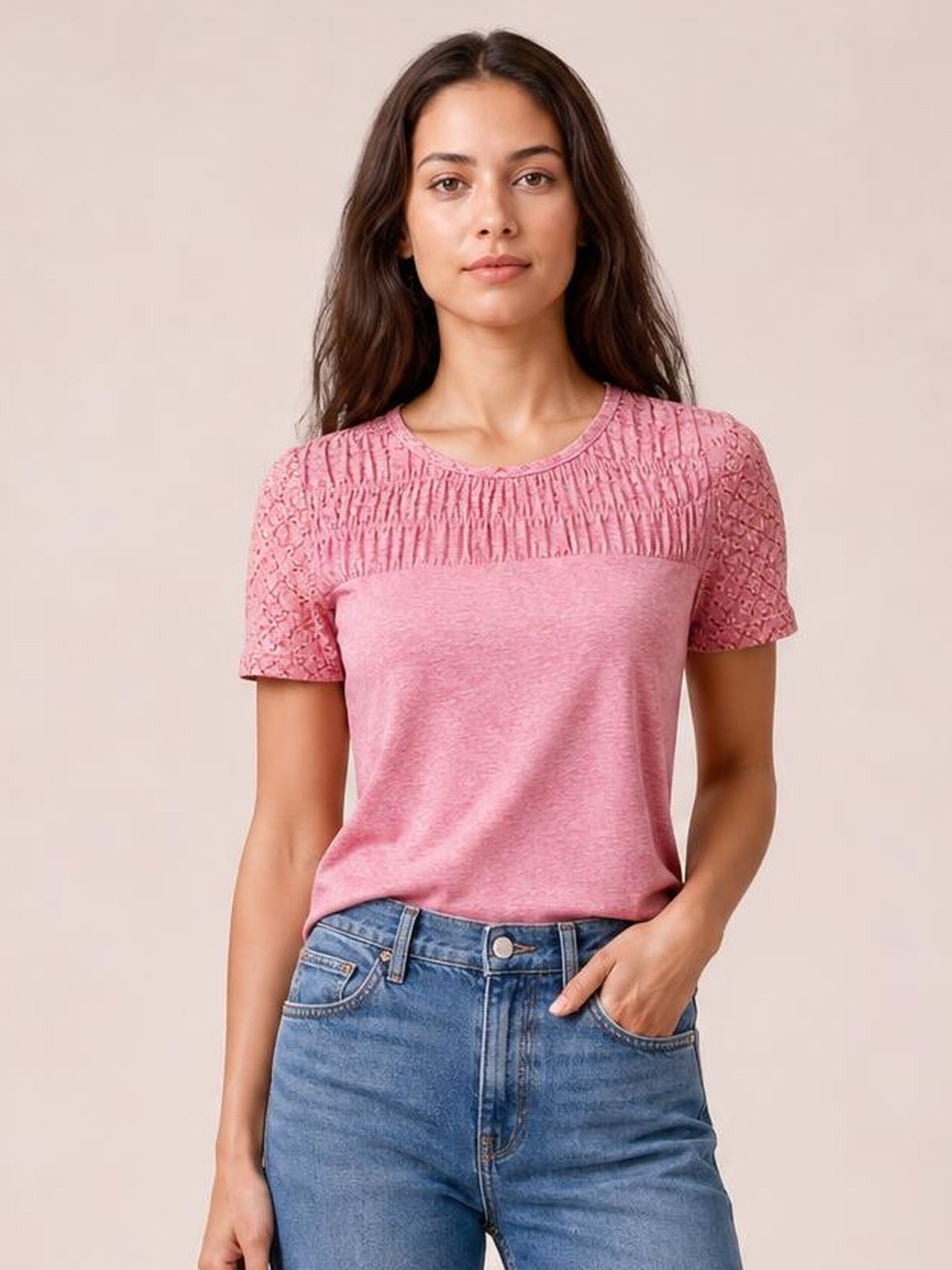 Model wearing a pink smocked round neck short sleeve T-shirt with semi-sheer lace sleeves, cutout details, and a relaxed silhouette.