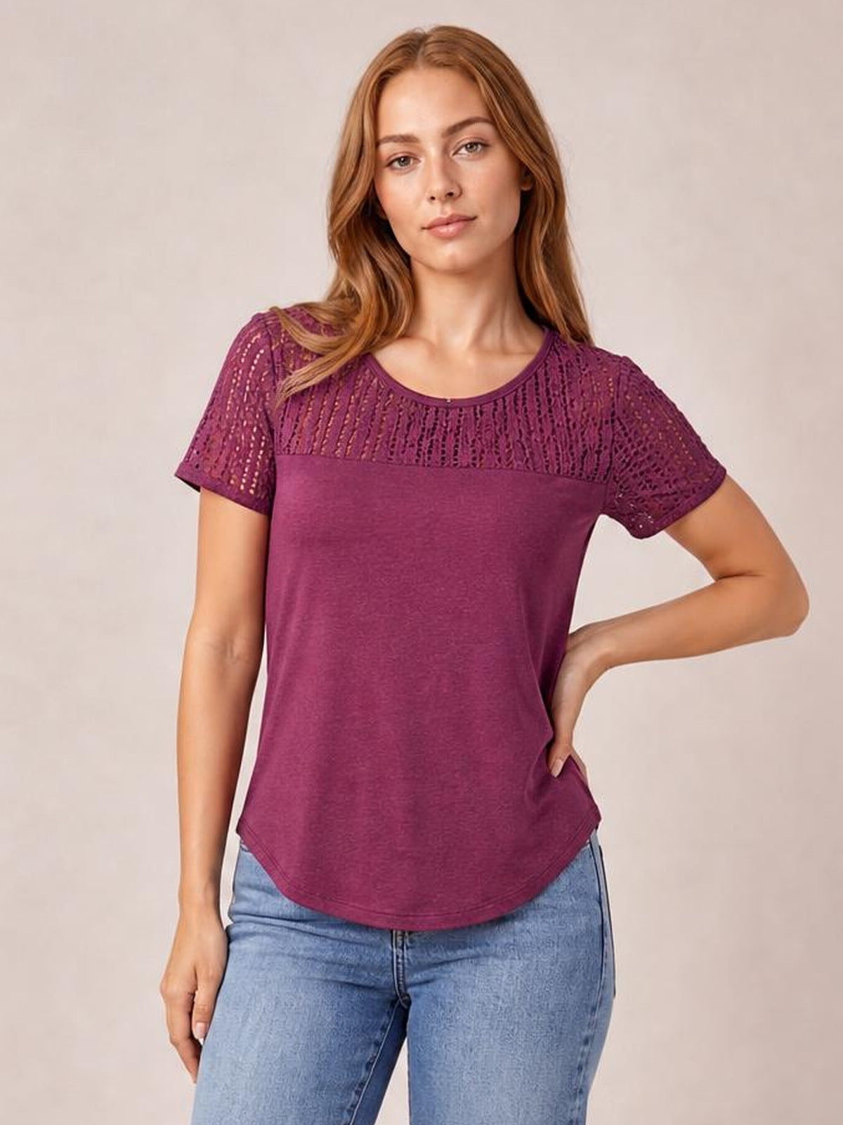 A model poses with one hand on her hip in a burgundy smocked round neck short sleeve T-shirt with semi-sheer cutout panels and a relaxed curved hem.