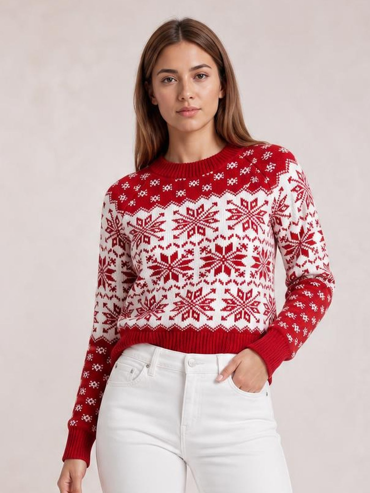 Model wearing a red and white snowflake pattern long sleeve sweater with a crew neck, ribbed trim, and relaxed silhouette, posing with one hand in her pocket.