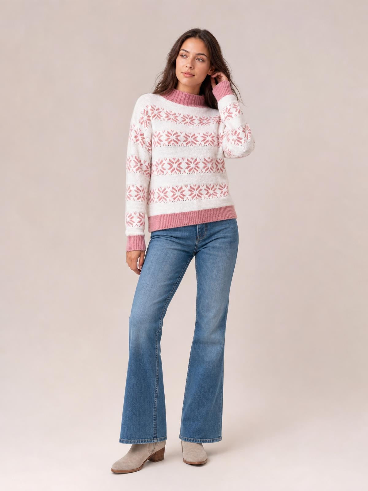 Model poses in a white snowflake pattern mock neck sweater with pink ribbed cuffs, collar, and hem, featuring a relaxed silhouette and long sleeves.
