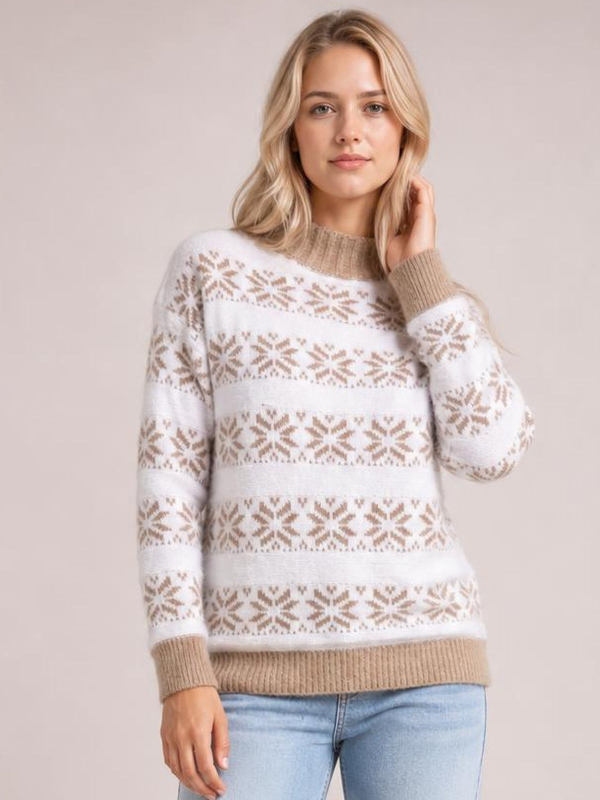 A model poses in a white snowflake pattern mock neck sweater with a relaxed silhouette, tan ribbed collar, cuffs and hem, and long sleeves.