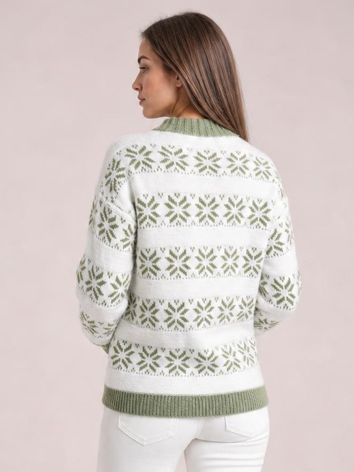 A model turns to show the back of a white snowflake pattern mock neck sweater with sage-green ribbed trim, long sleeves, and a relaxed silhouette.