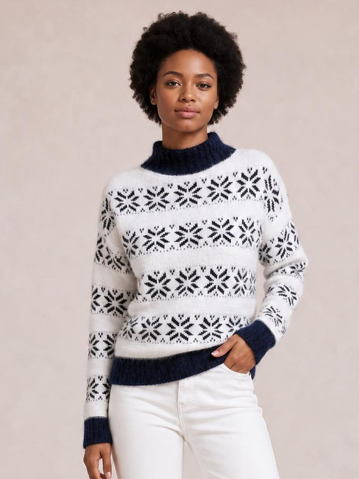 Model poses with one hand in her pocket wearing a white snowflake-pattern mock neck sweater with navy ribbed collar, cuffs, hem, and a relaxed silhouette.