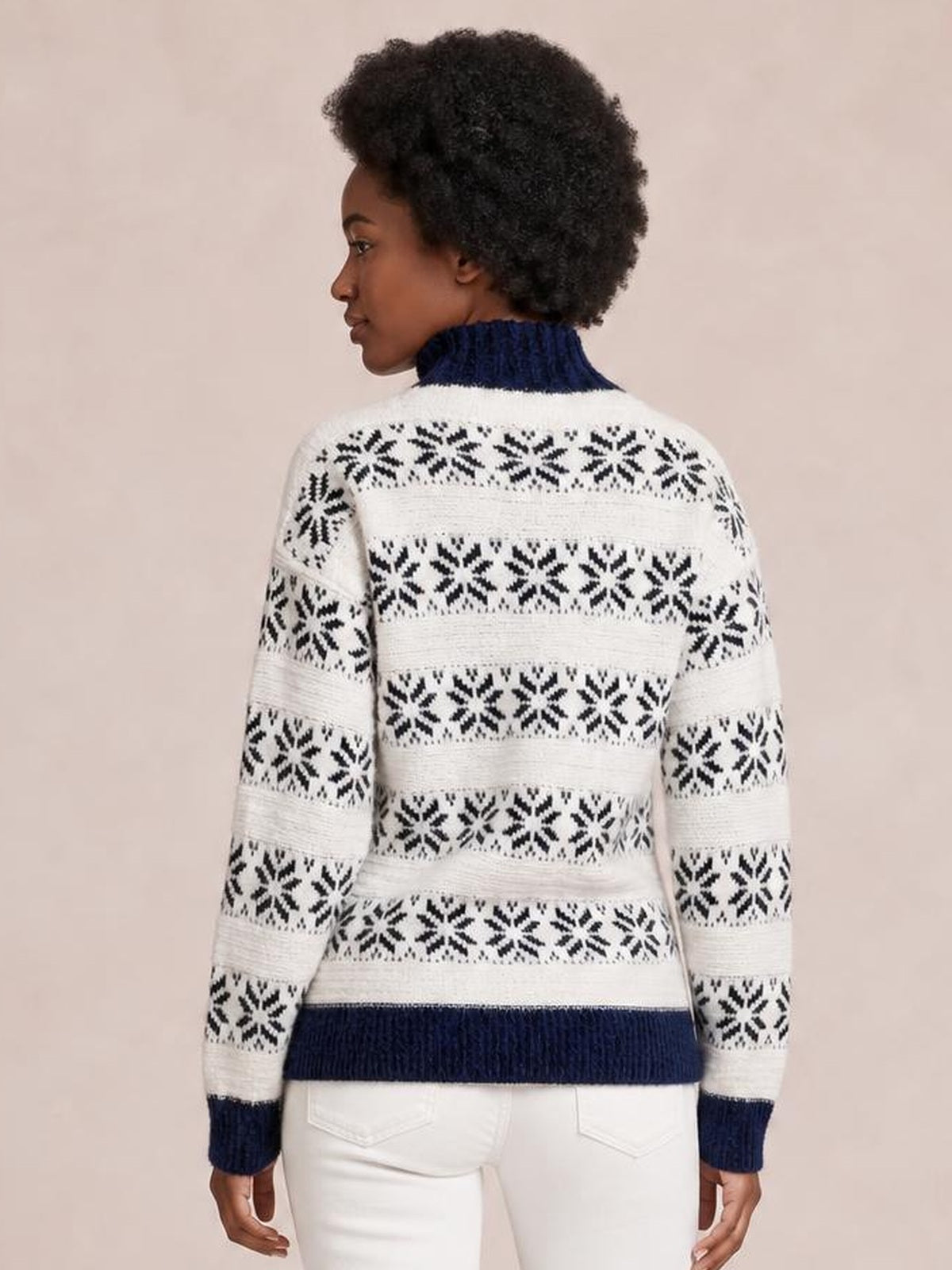 A model shows the back of a white snowflake-pattern mock neck sweater with navy ribbed collar, cuffs, hem, long sleeves, and a relaxed silhouette.