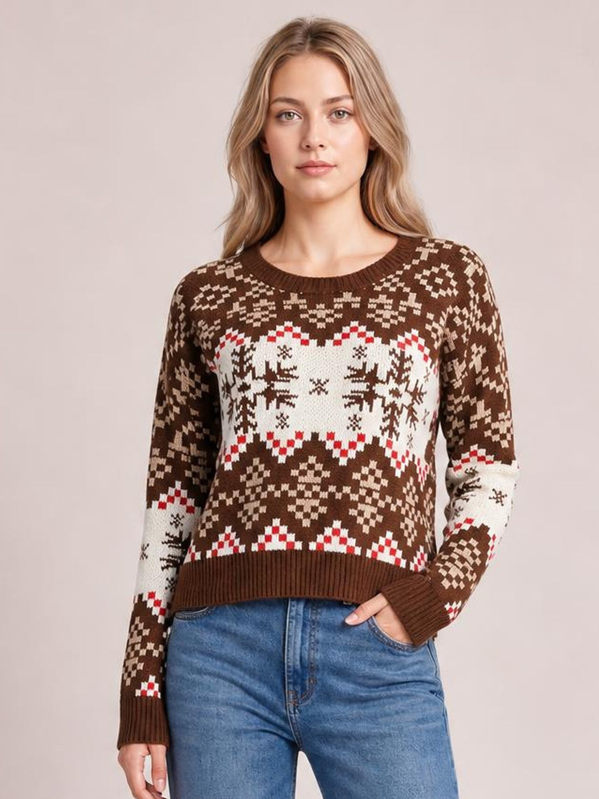 Model wearing a brown snowflake pattern round neck sweater with long sleeves, ribbed neckline and cuffs, relaxed silhouette, and a hand in her jeans pocket.