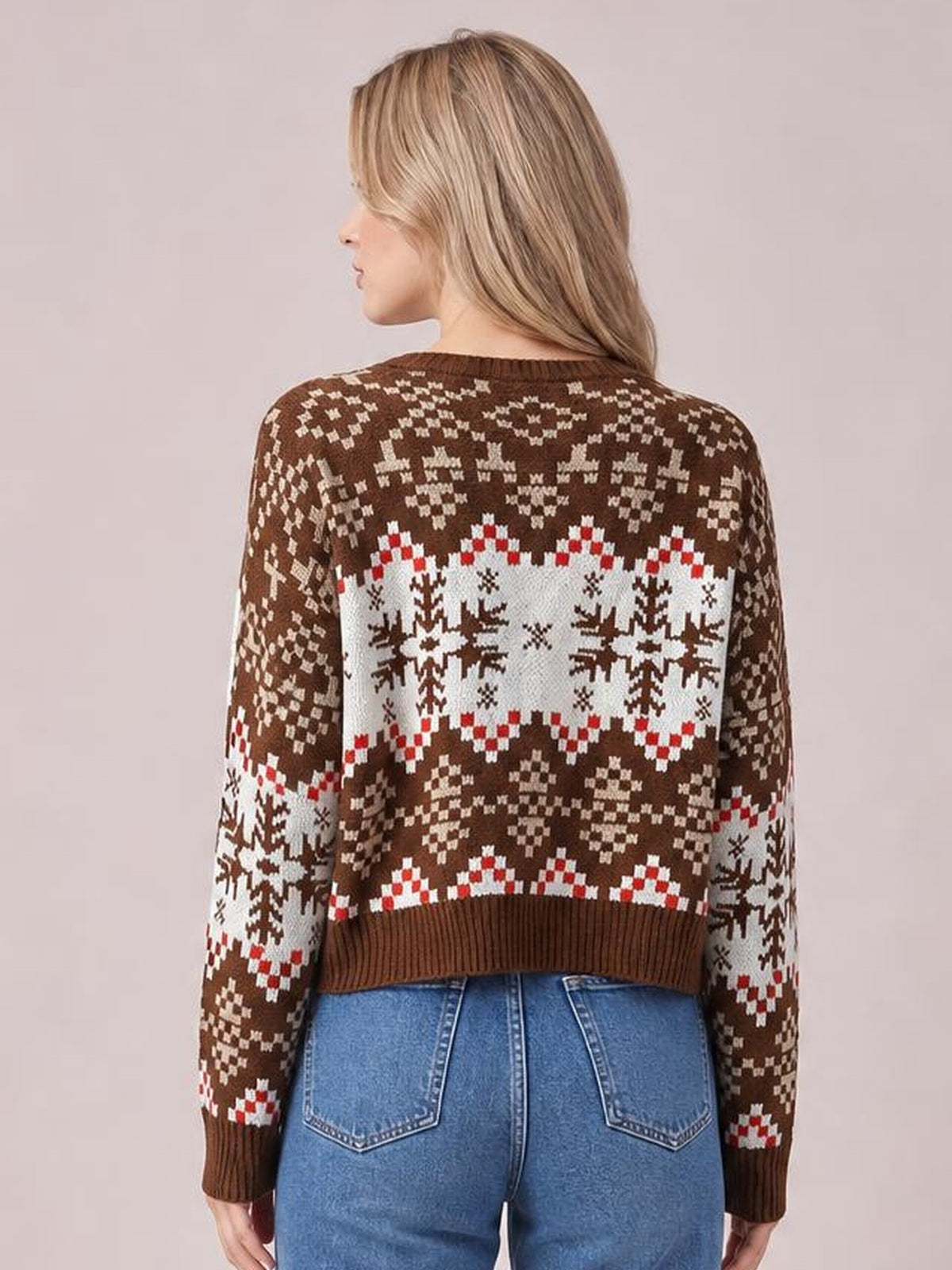 Model shown from behind wearing a brown round-neck sweater with white and red snowflake patterns, long sleeves, ribbed cuffs, and a cropped silhouette.