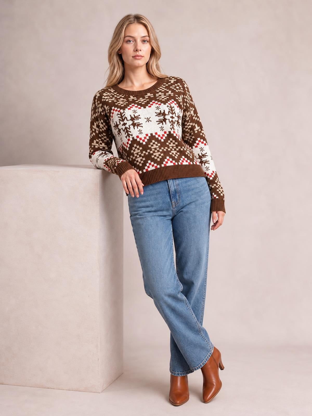 Model wears a brown snowflake pattern round neck sweater with a white and red geometric knit design, ribbed cuffs and hem, and a relaxed silhouette.