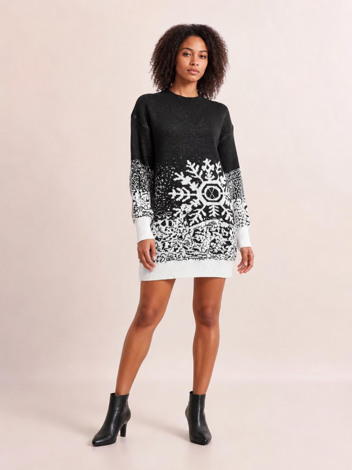 Model poses in a black-and-white snowflake pattern sweater dress with long sleeves, ribbed neckline and cuffs, and a relaxed straight silhouette.