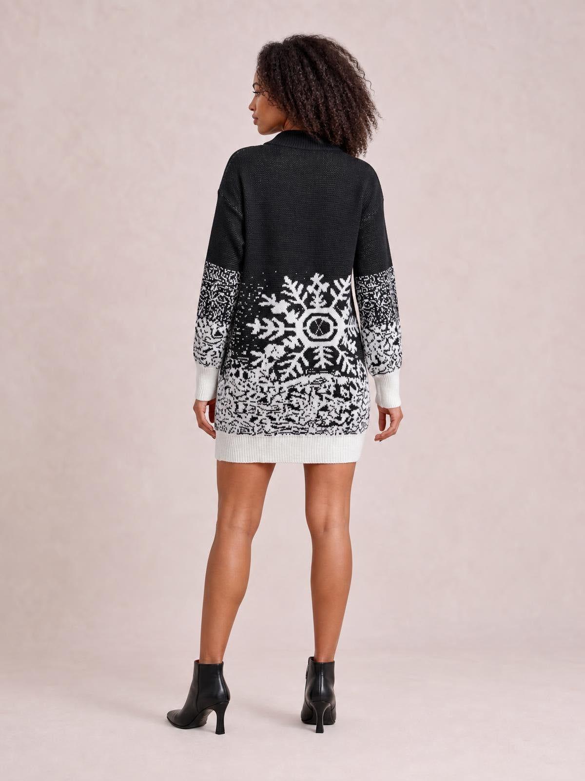 A model stands with her back turned in a black-and-white snowflake pattern sweater dress with long sleeves, a ribbed collar, cuffs, hem, and relaxed silhouette.