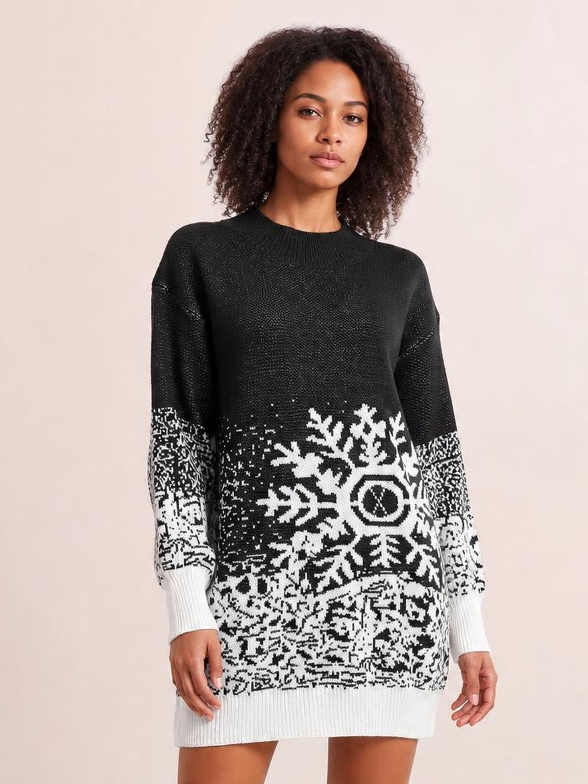 Model wears a black-and-white snowflake pattern sweater dress with long sleeves, ribbed crew neckline, cuffs and hem, and a relaxed straight silhouette.