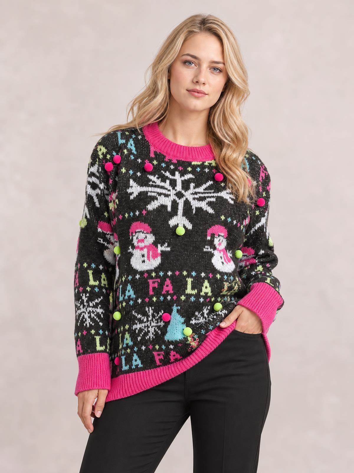 Model poses in a relaxed stance wearing a black Snowman contrast trim round neck sweater with pink ribbed edges, colorful snowflake and snowman motifs, and a relaxed silhouette.