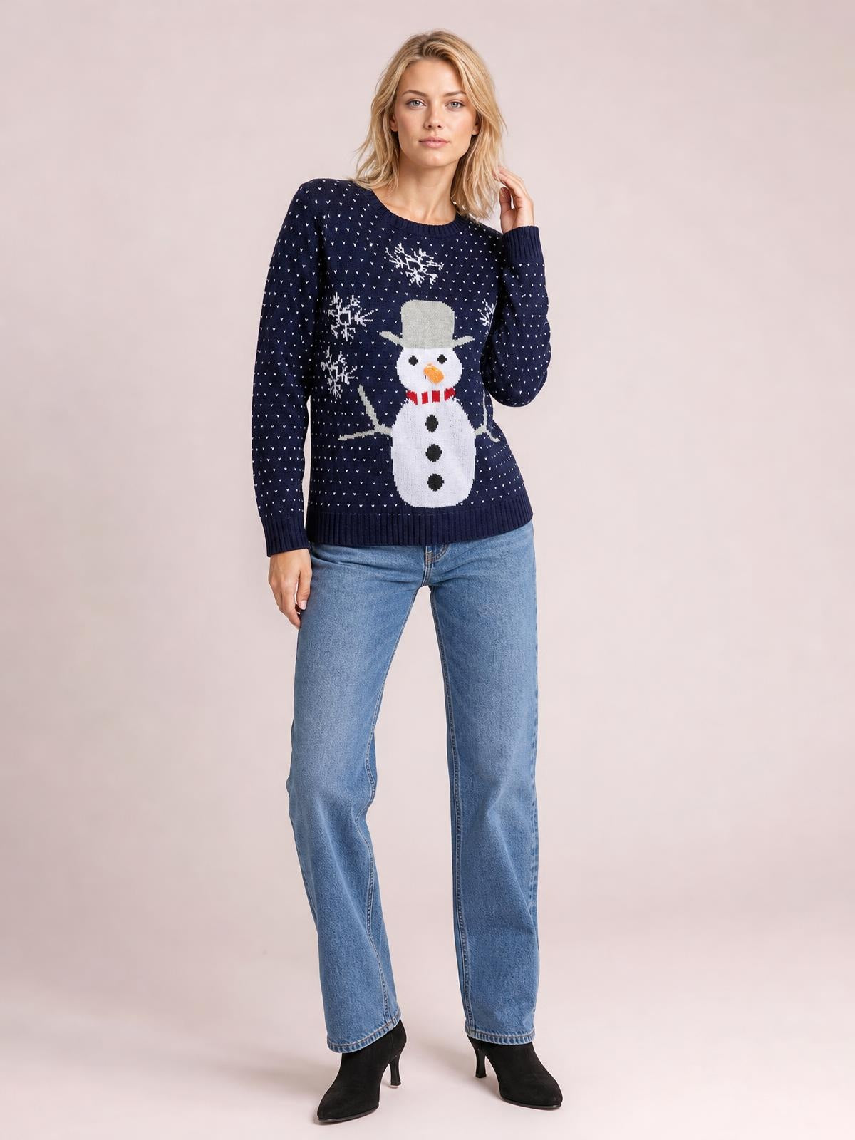 A woman wears a navy snowman graphic raglan sleeve sweater with a relaxed silhouette, crew neck, and ribbed cuffs and hem, posing with one hand in her hair.
