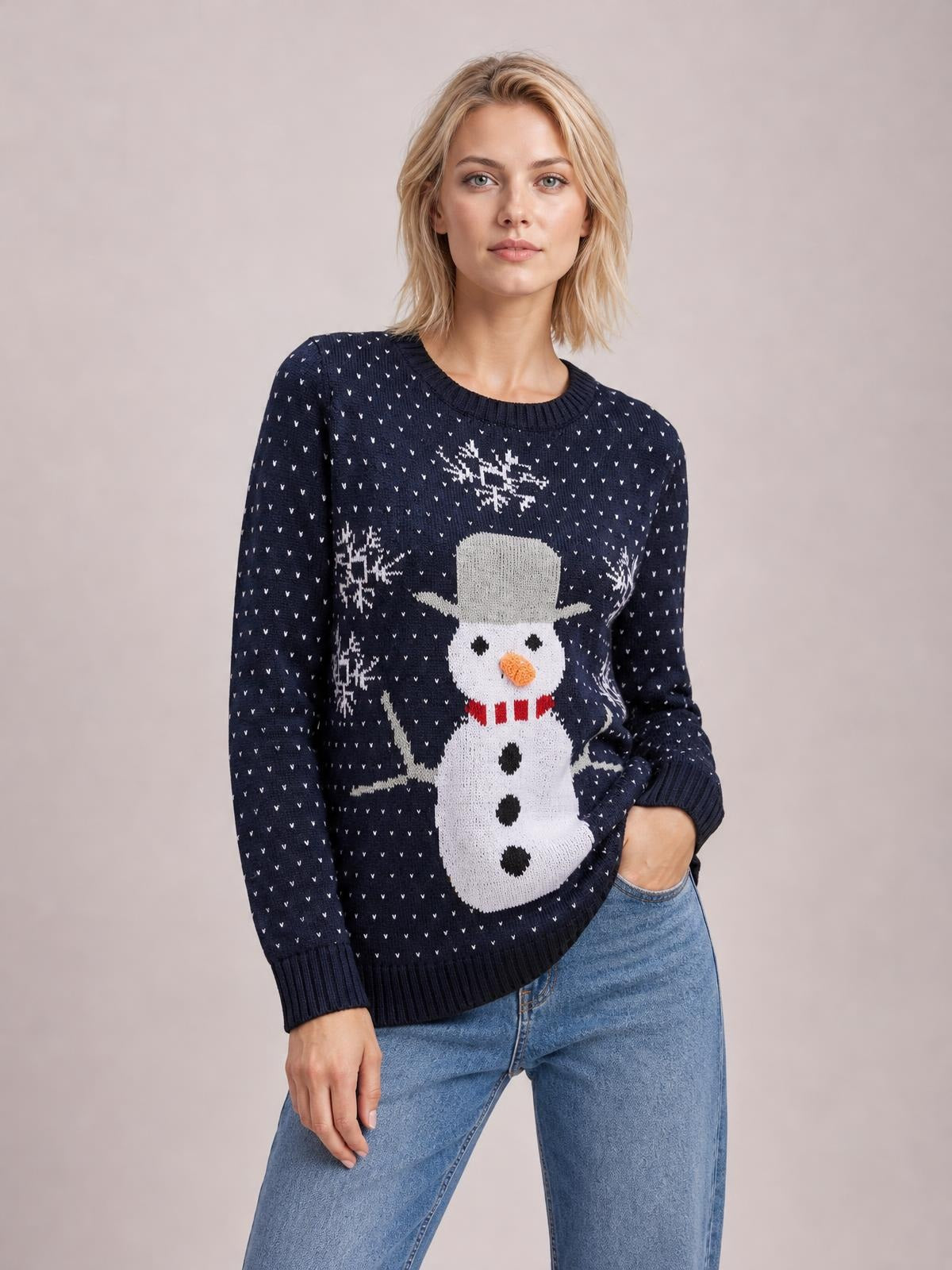 Model wears a navy Snowman Graphic Raglan Sleeve Sweater with ribbed crew neckline, cuffs and hem, relaxed silhouette, and one hand in her jeans pocket.