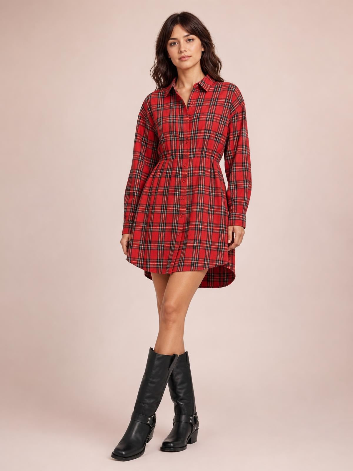 A model poses in a red plaid shirt dress with long sleeves, a button-down front, relaxed silhouette, and curved shirttail hem.