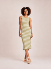A model stands with crossed legs in a fitted olive and cream striped sleeveless sweater-knit maxi dress with a crew neckline and ruffled hem.