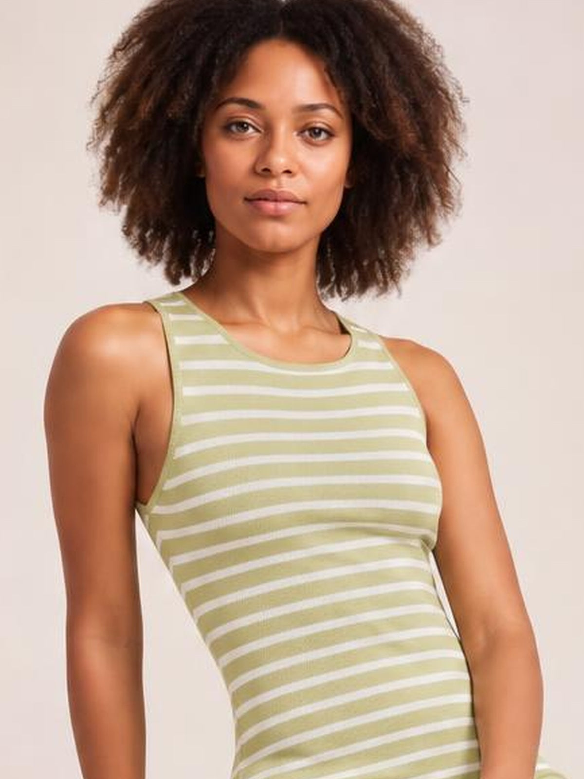 A model wears a sage green and white striped sleeveless sweater-knit maxi dress with a round neckline and fitted silhouette.