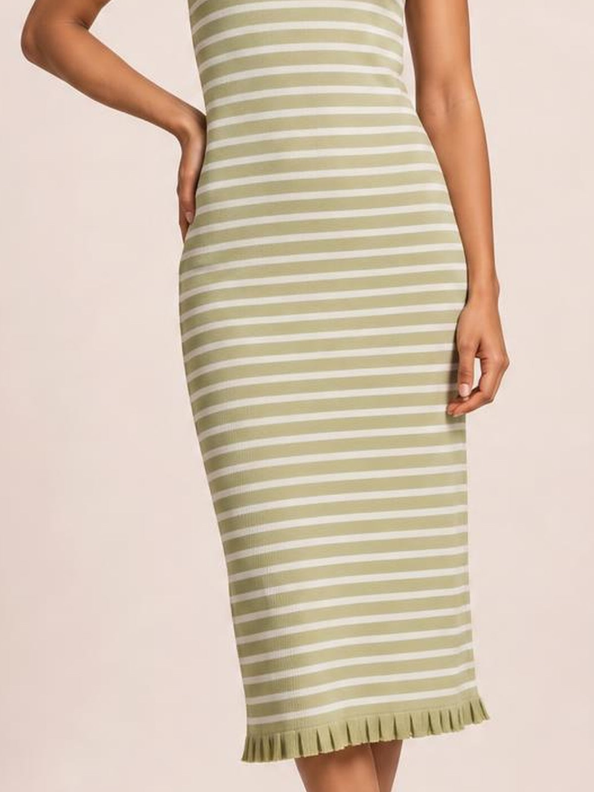 A model poses in a fitted olive green and white striped sleeveless sweater knit maxi dress with a structured silhouette and ruffled hem.