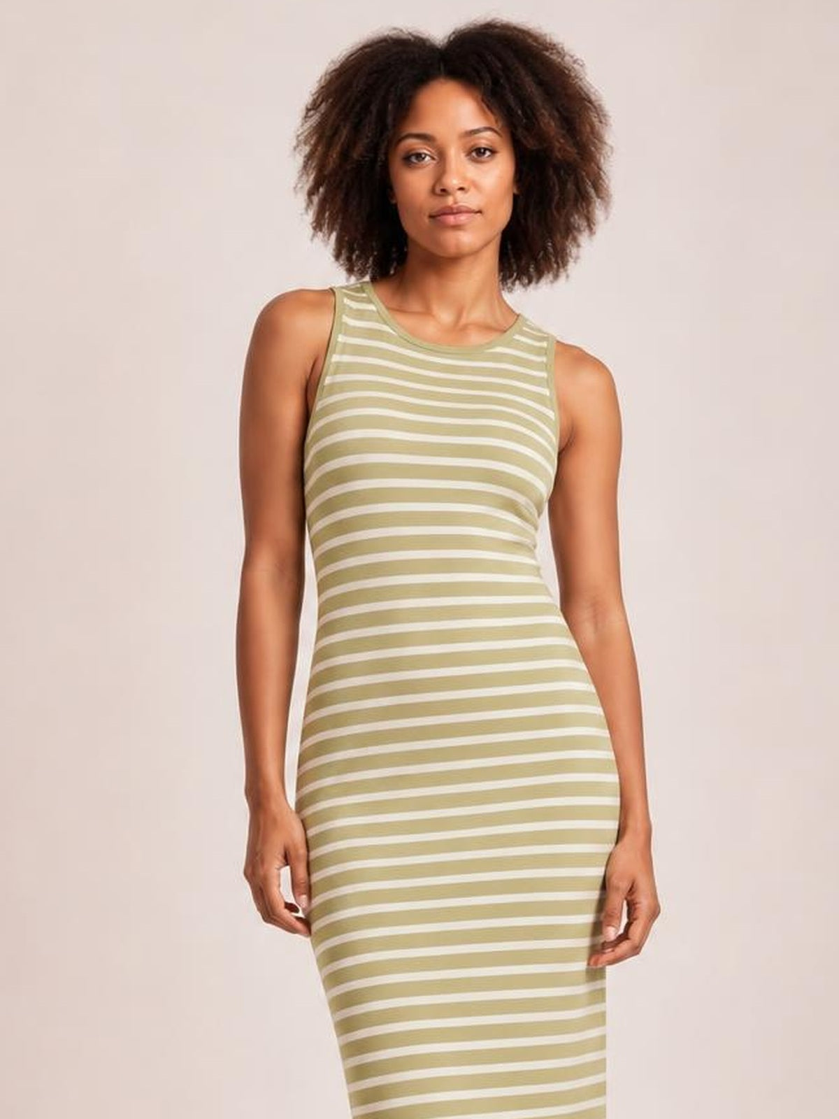 Model stands with arms at her sides in an olive green and white striped sleeveless sweater knit maxi dress with a fitted silhouette and crew neckline.