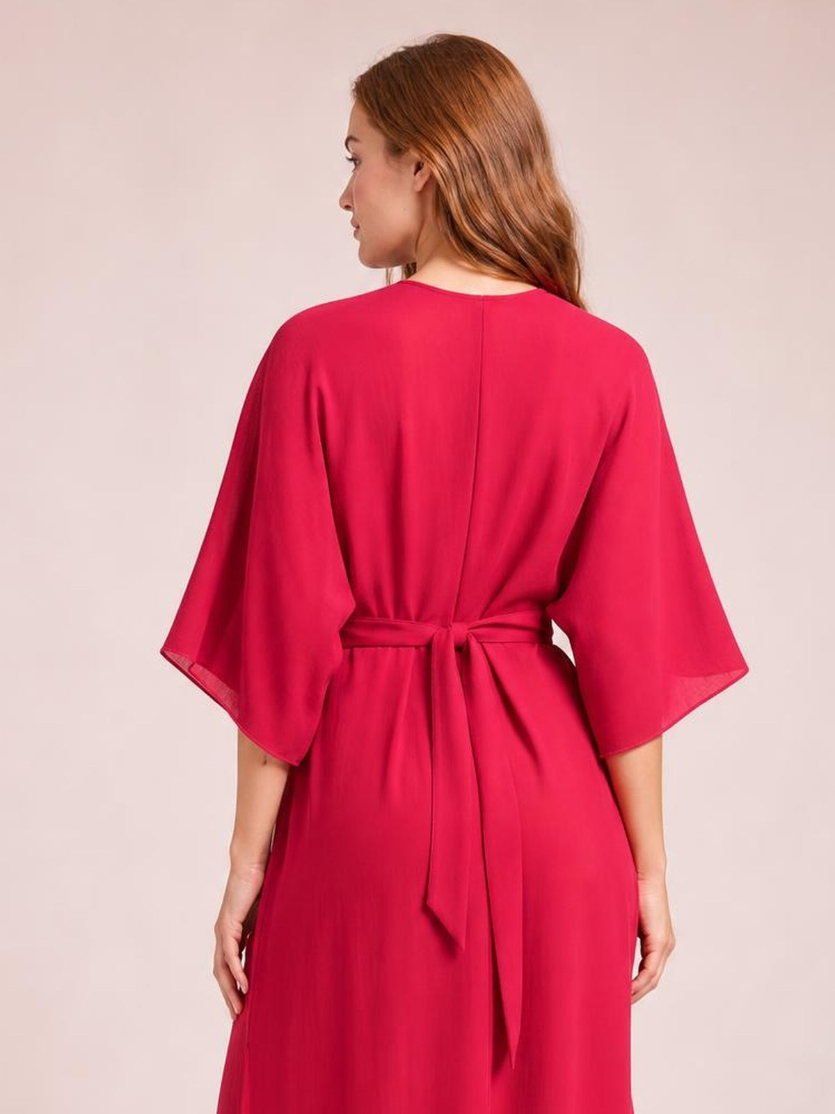 Model shown from the back wearing a solid fuchsia cover-up with flowing flutter sleeves, a relaxed silhouette, and a tied waist sash.
