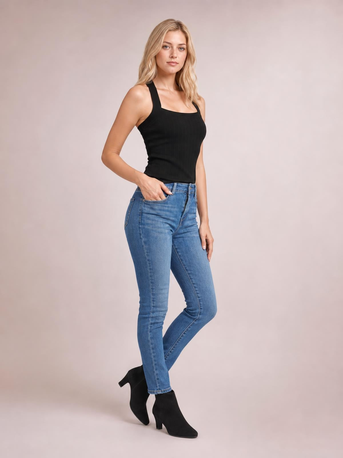Model poses with one hand in her jeans pocket, wearing a solid black knit cami with wide straps, a square neckline, and a fitted silhouette.