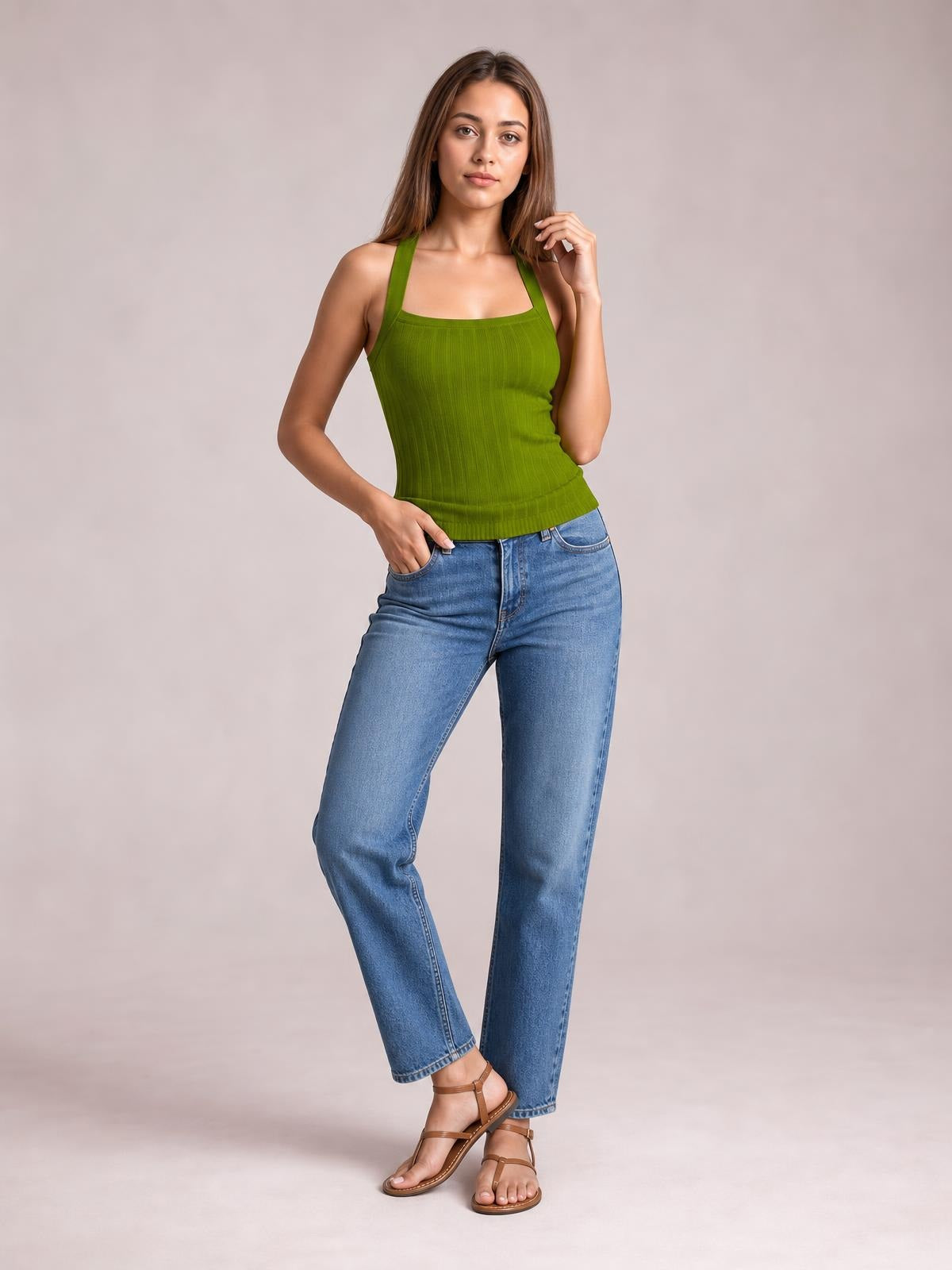 Model poses in a solid green halter neck knit cami with a fitted silhouette, wide straps, subtle vertical texture, and a ribbed hem.