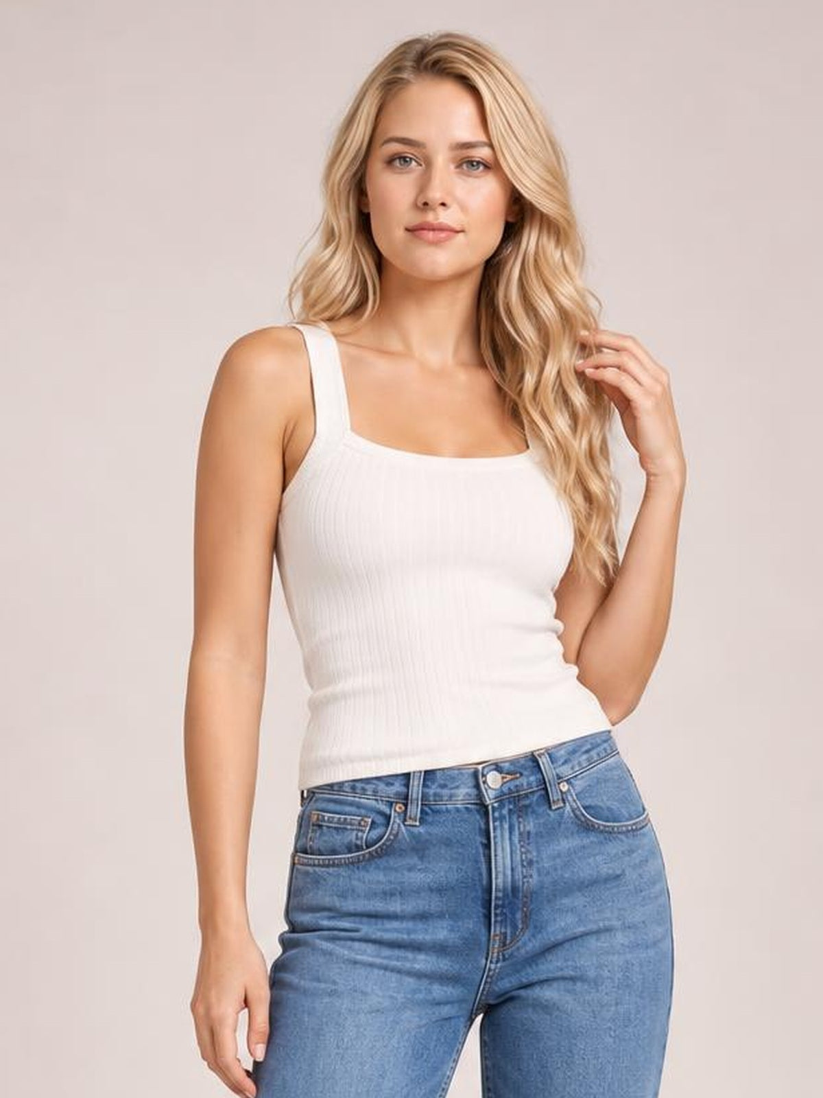 Model poses in a fitted solid white knit cami with wide shoulder straps, a square neckline, subtle ribbed texture, and a slim silhouette.
