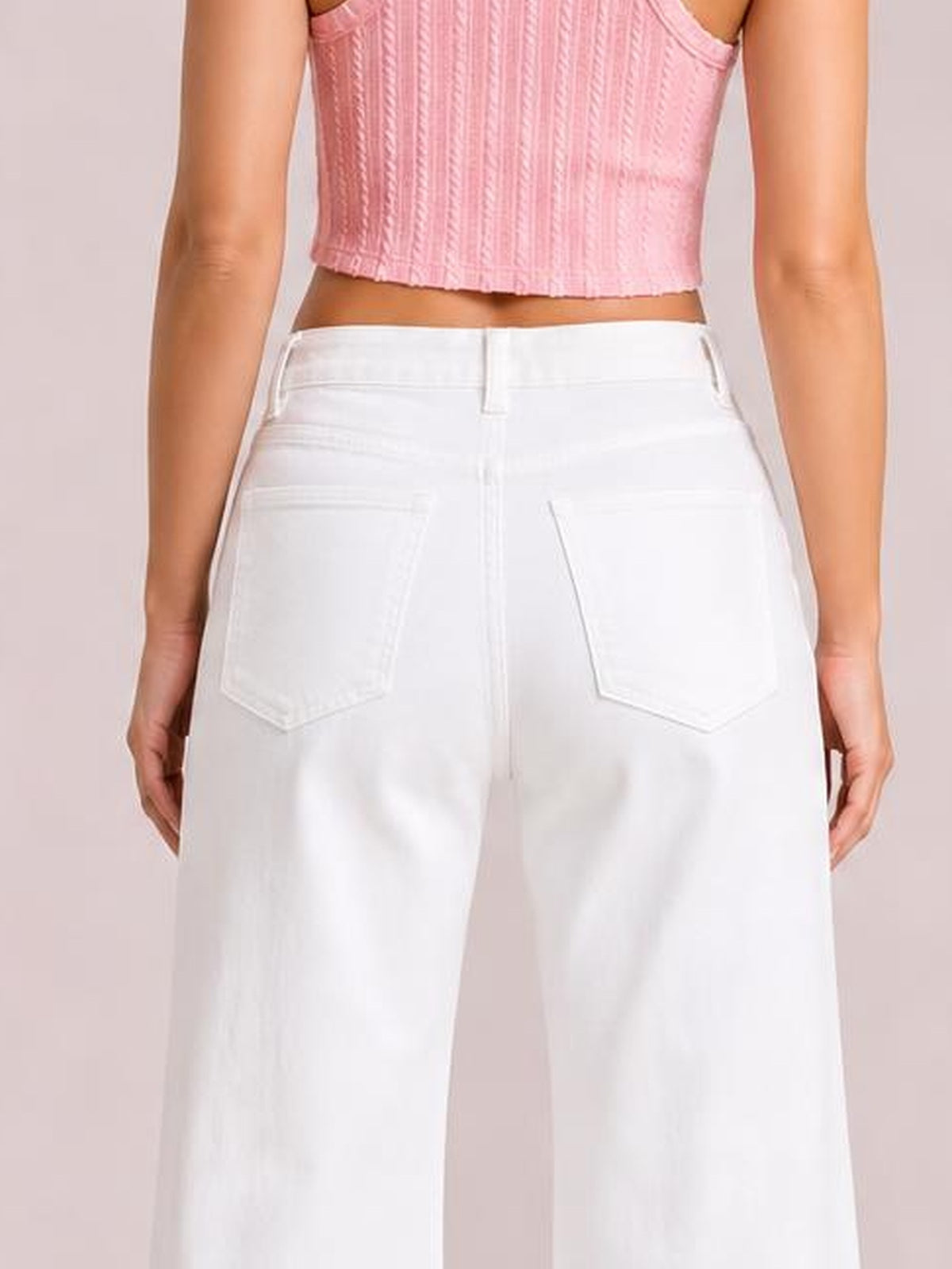 A model shown from behind wears solid white casual jeans with a high waistband, belt loops, rear patch pockets, and a relaxed loose-leg silhouette.