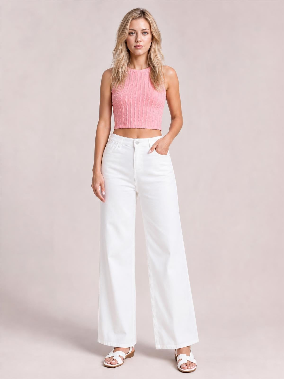 A model stands facing forward with one hand in a pocket, wearing solid white casual jeans with a high waist, button fly, pockets, and a loose wide-leg silhouette.
