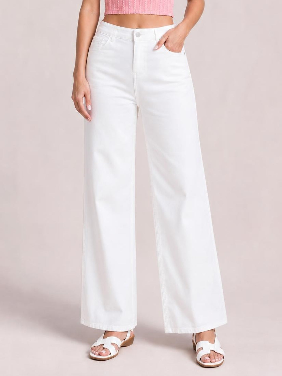 Model wearing solid white casual jeans with a high-rise waist, button fly, front pockets, and a loose wide-leg silhouette, hand resting in a pocket.