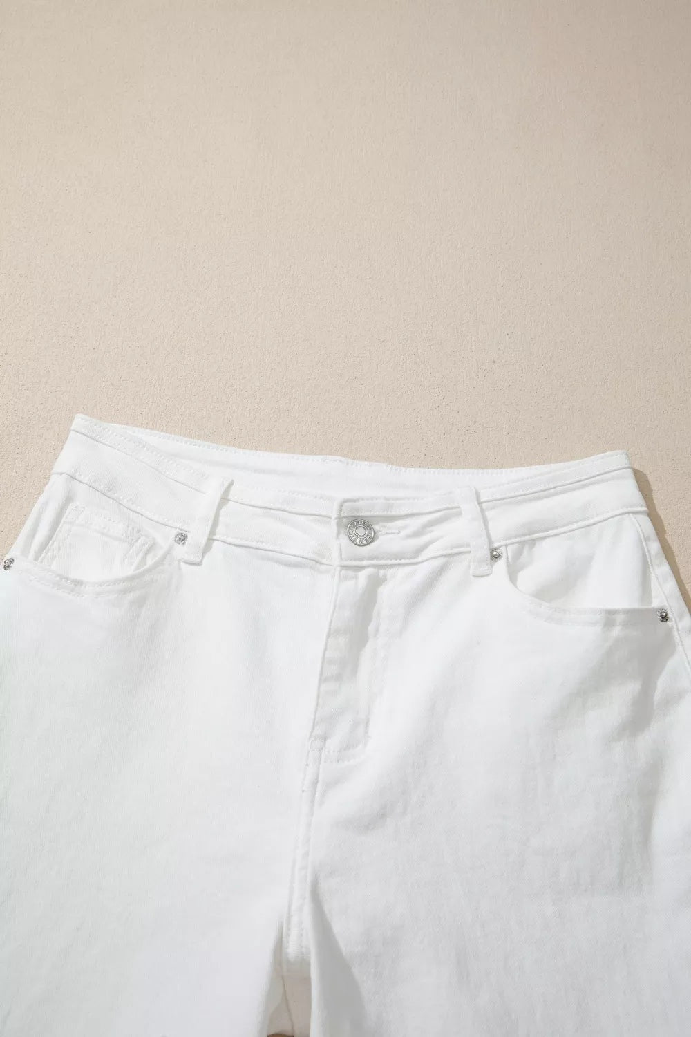 White solid-color casual jeans laid flat, featuring a relaxed loose-leg silhouette, belt loops, button closure, zip fly, front pockets, and sturdy seam construction.
