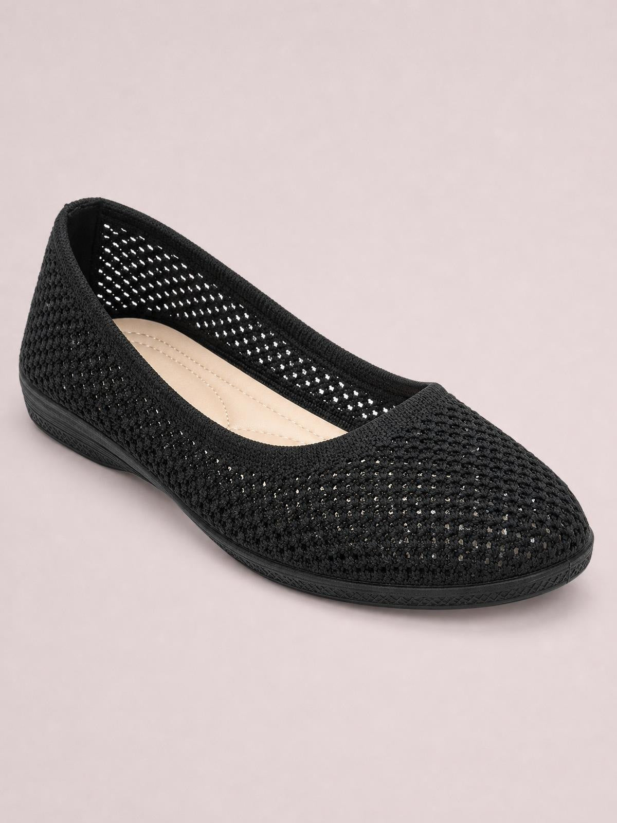 Black solid-color mesh flat slip-on shoe with a rounded toe, woven open-knit upper, low rubber sole, and cushioned beige insole.
