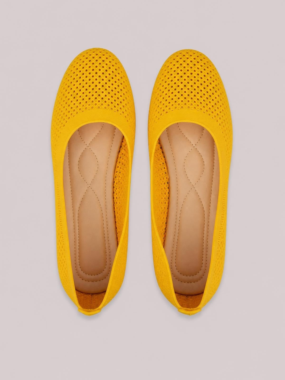 Bright yellow mesh flat slip-on shoes with perforated uppers, rounded toes, low heels, tan cushioned insoles, and rubber soles.