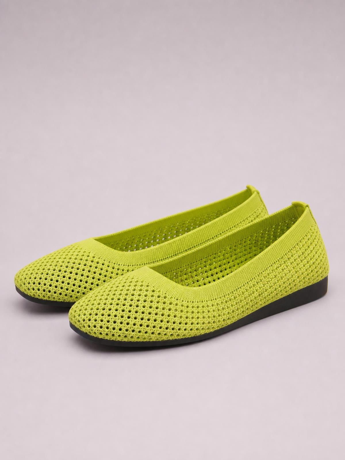 Lime green mesh flat slip-ons feature rounded toes, breathable perforated uppers, elastic openings, and low black rubber soles.