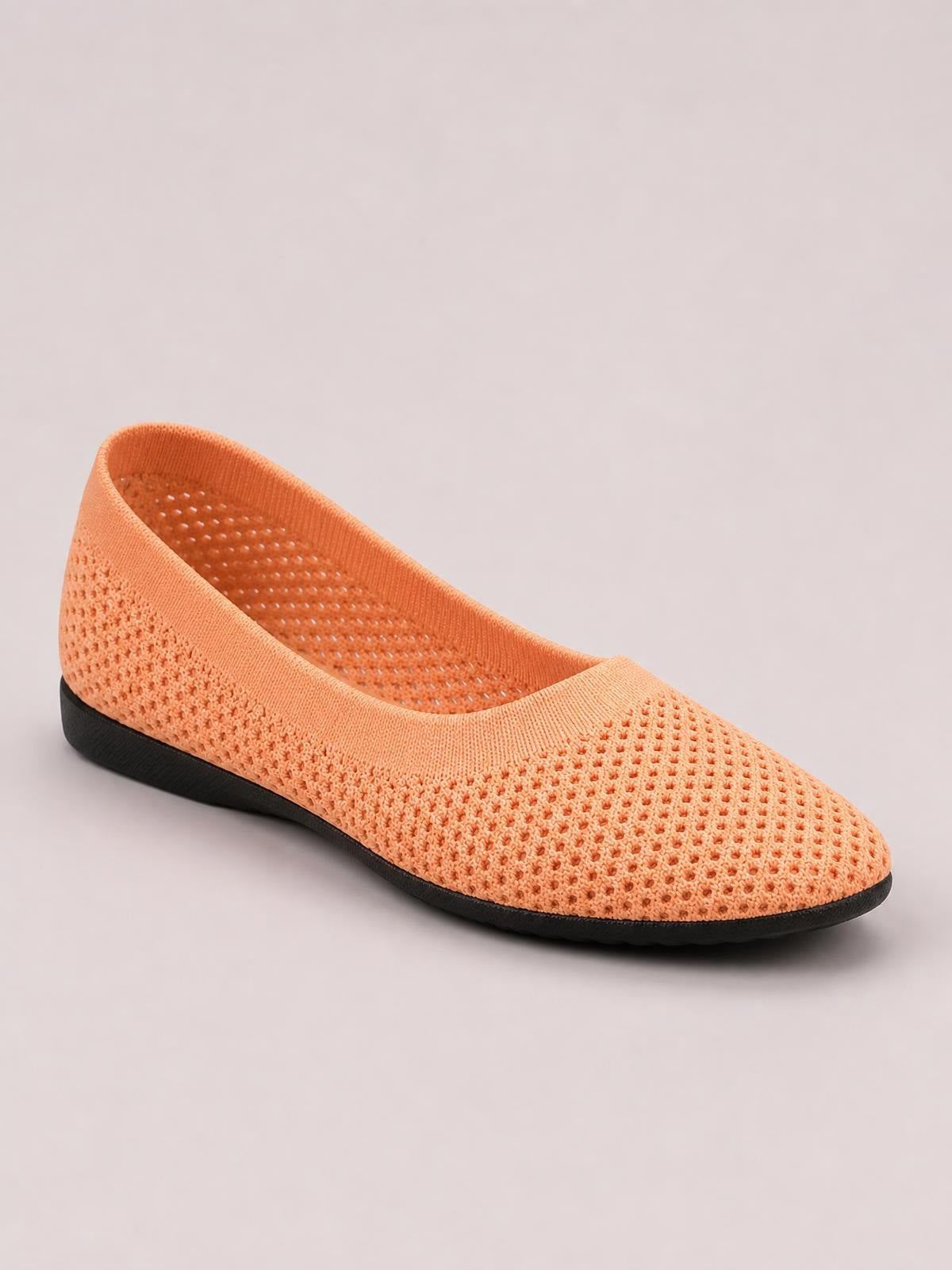 Peach solid-color mesh flat slip-on with a rounded toe, low profile, breathable perforated upper, and contrasting black rubber sole.